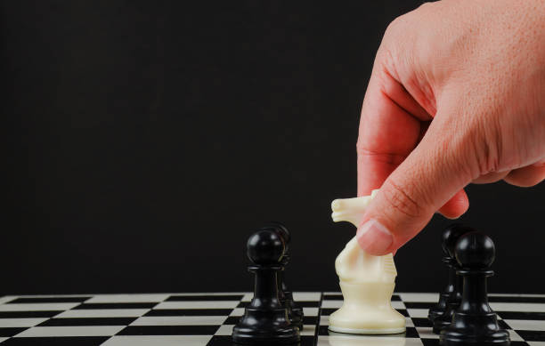 istock Hand man making move with white horse (knight) on chess board 1175477962
