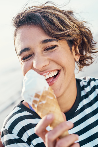 Cropped shot of a young woman enjoying ice cream outdoors