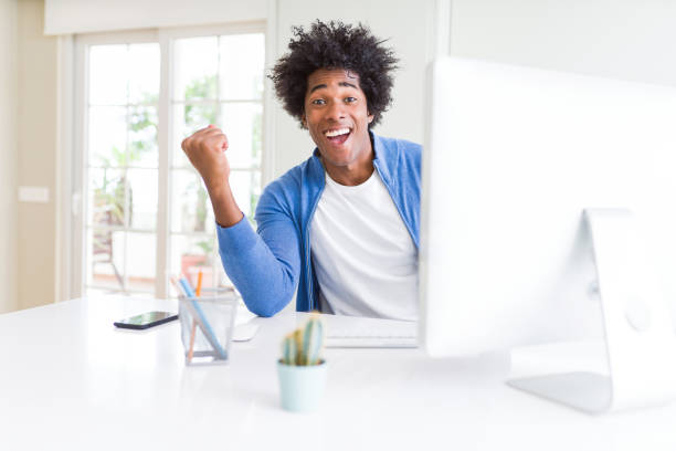 istock African American man working using computer screaming proud and celebrating victory and success very excited, cheering emotion 1175488998
