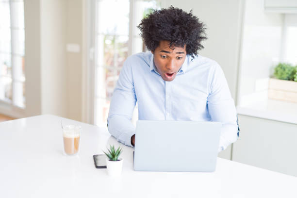 istock African American business man working using laptop scared in shock with a surprise face, afraid and excited with fear expression 1175491448