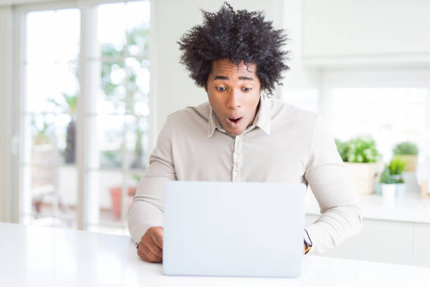 istock African American man working using laptop scared in shock with a surprise face, afraid and excited with fear expression 1175491947