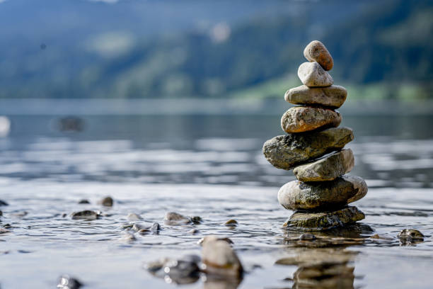 Piles of stones in the water in the mountains Alpsee on the shore with stones cairn stock pictures, royalty-free photos & images