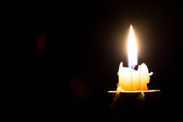 istock burning candle on a dark background and blurry highlights on an empty black background on the left side 1175494601