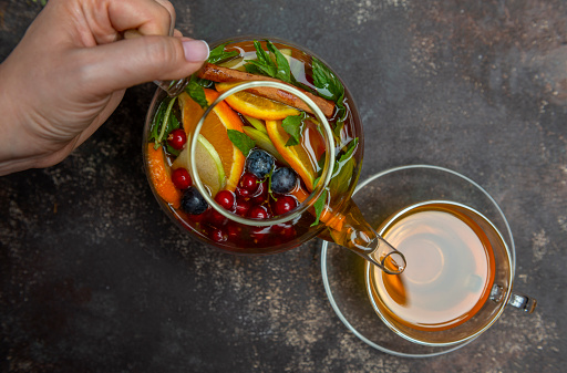 Herb tea and fresh fruits in the glass pot.