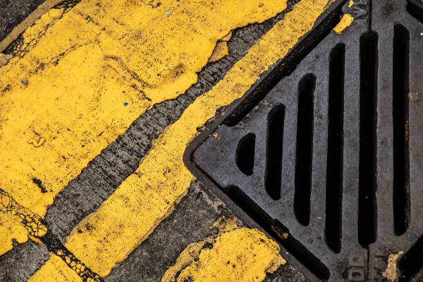 istock Storm drain and yellow road markings on the old asphalt 1175497337