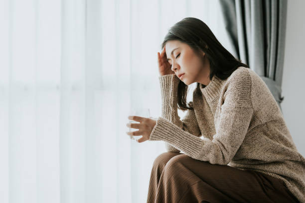 woman feeling headache from flu and cold Sick Asian woman feeling headache from flu and cold holding a glass of water, health problems treatment headache stock pictures, royalty-free photos & images