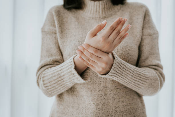 Woman suffering from wrist pain Cropped shot of woman in sweater holding her wrist pain arthritis stock pictures, royalty-free photos & images