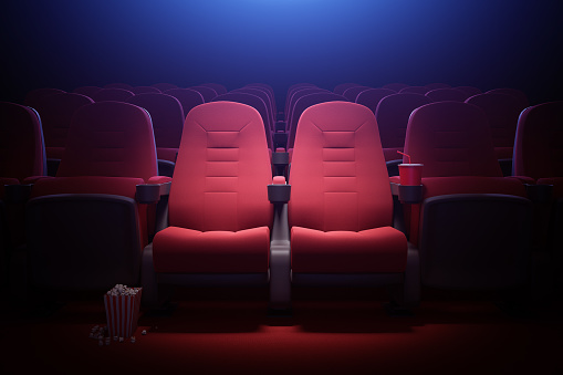 Interior of empty cinema with rows of red seats with cup holders and popcorn. Concept of entertainment. 3d rendering toned image