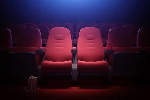 Interior of empty cinema with rows of red seats with cup holders and popcorn. Concept of entertainment. 3d rendering toned image