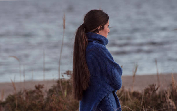 istock woman with sweater walking on the beach 1175498150