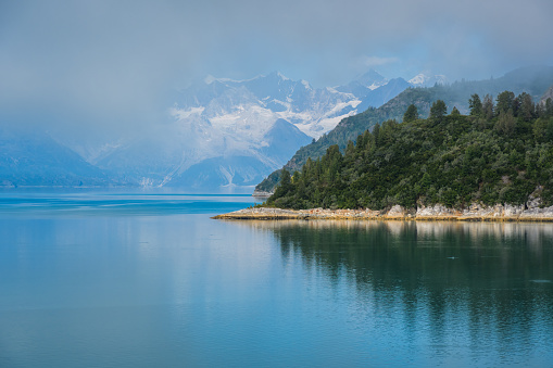 Remote coastline on a misty morning in the Alaska inside passage with snow capped mountains in the background