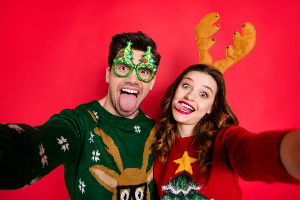 Photo of childish lady and guy at newyear costume party making selfies wear ugly knitted pullovers isolated red color background Photo of childish lady and guy at newyear costume party making selfies, wear ugly knitted pullovers isolated red color background ugliness photos stock pictures, royalty-free photos & images