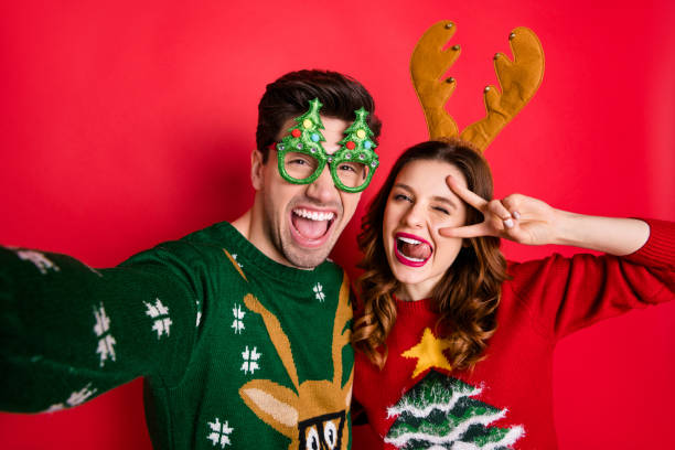 Photo of crazy couple making selfies sticking tongues winking eyes v-signing wear funky ugly ornaments jumpers isolated red color background Photo of crazy couple making selfies sticking tongues winking eyes v-signing, wear funky ugly ornaments jumpers isolated red color background afternoon picture stock pictures, royalty-free photos & images