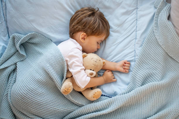 foto del bambino che dorme insieme all'orsacchiotto. - baby sleeping bedding teddy bear foto e immagini stock