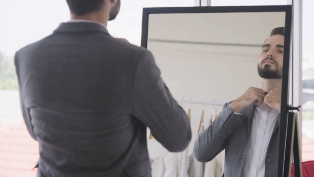 istock Man in formal suit getting dressed in dressing room for work or wedding. 1175501586