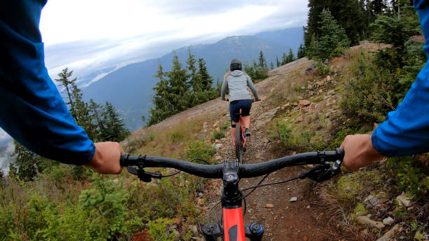 istock Female mountain biker rides on path through forest 1175504829