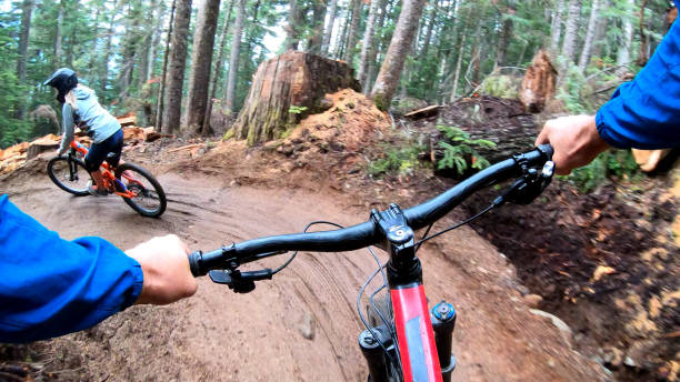 istock Female mountain biker rides on path through forest 1175505466