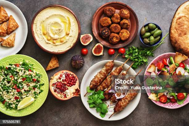 Arabic And Middle Eastern Dinner Table Hummus Tabbouleh Salad Fattoush Salad Pita Meat Kebab Falafel Baklava Pomegranate Set Of Arabian Dishestop View Flat Lay Stock Photo - Download Image Now