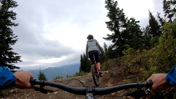 istock Female mountain biker rides on path through forest 1175506110