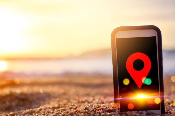 istock Smart phone and sand sunset beach with red navigator gps location abstract background. 1175512027