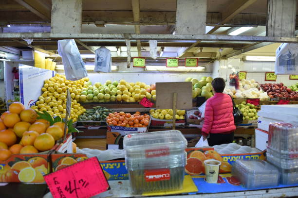 Jerusalem, Israel - December 23, 2018: colourful fruit and vegetables displayed on a stall in Machane Yehuda Market in Jerusalem, Israel. Some unidentified people in the background.