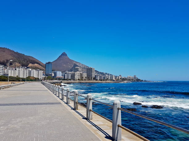 montañas, hoteles y aguas azules profundas con olas en el sea point, paseo marítimo en ciudad del cabo sudáfrica. - cape point fotografías e imágenes de stock