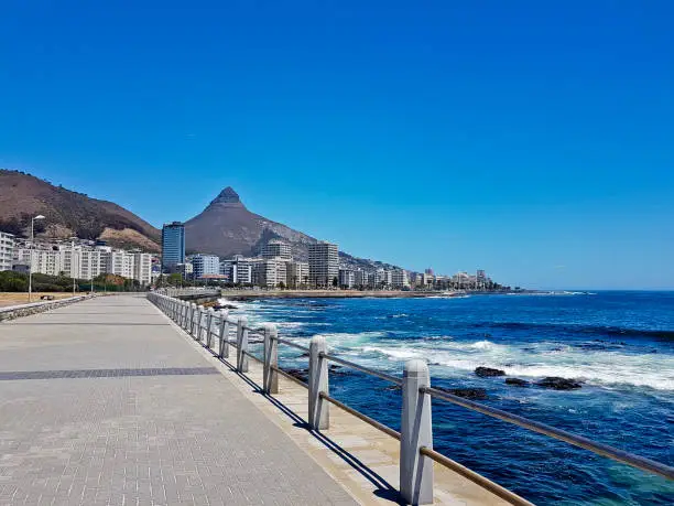 Mountains, hotels and deep blue water with waves at the Sea Point, beach promenade in Cape Town South Africa.