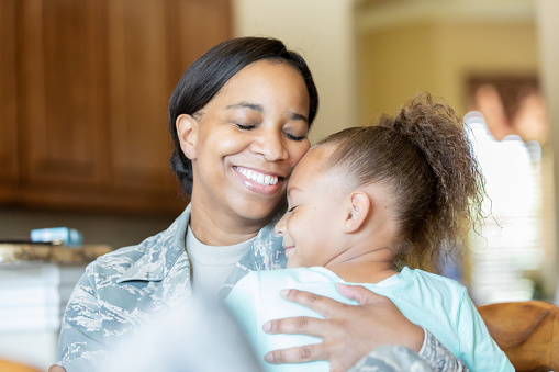 Veteran mother embracing daughter before leaving for tour of duty