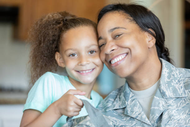 istock Elementary age little girl holds soldier mother's uniform backpack 1175525069