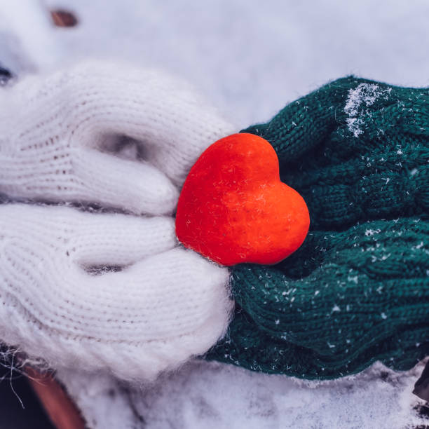 hands in gloves holding heart closeup on winter snow background. toned. valentine's day and love concept, square - glove winter wool touching imagens e fotografias de stock