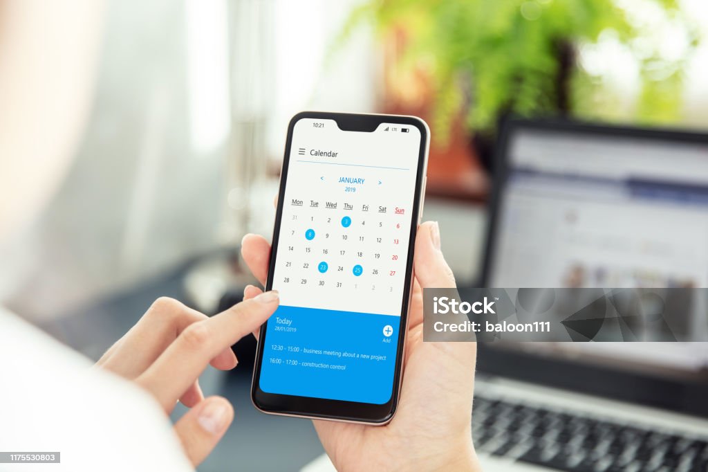 Businesswoman points smartphone screen and checks calendar on application. Application on screen created in graphic program Calendar Stock Photo