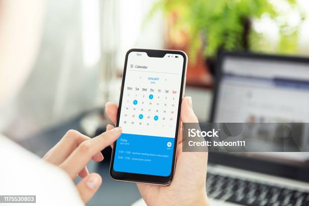 Businesswoman Points Smartphone Screen And Checks Calendar On Application Application On Screen Created In Graphic Program Stock Photo - Download Image Now