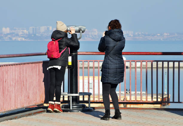 Girls enjoy sea view through an optical panoramic observer. Port of Odessa. September 11, 2018