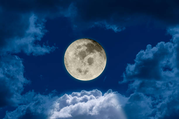 istock Big bright and shining full moon against a dark night sky dramatic seen through a hole in the clouds. 1175534488