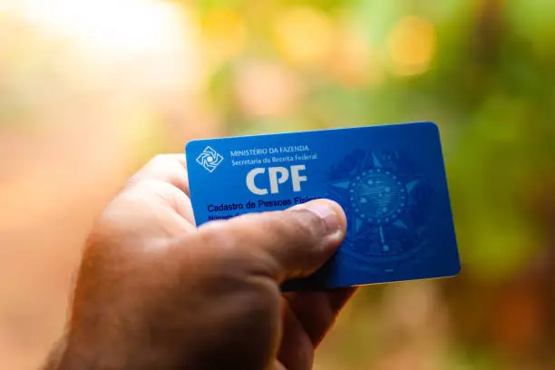 Photo of Man holding document  - Cadastro de Pessoa Física - (CPF). The document guarantees authenticity and integrity in electronic communication between people in Brazil