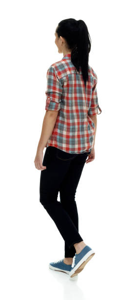 Full length / one person / rear view / back of 18-19 years old adult beautiful black hair / long hair / ponytail caucasian female / young women walking in front of white background wearing jeans / pants / lumberjack shirt / plaid shirt / button down shirt / shirt / canvas shoe who is happy / cheerful / cool attitude with hand by side longitud completa / una persona / vista trasera / parte posterior de 18-19 años adulto hermoso pelo negro / pelo largo / cola de caballo caucásico mujer / mujeres jóvenes caminando delante de fondo blanco que es feliz / alegre / actitud fresca con mano