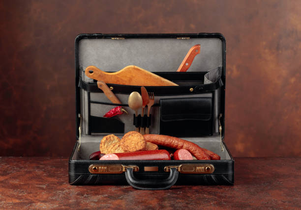istock Black leather case with sausage, cutlets and cutlery on brown table. 1175538690