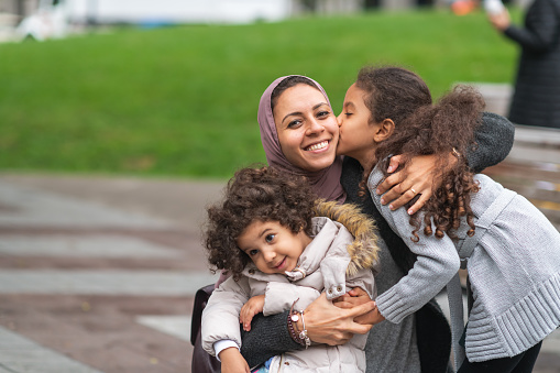 Madre musulmana abrazando hijas en el parque de la ciudad photo