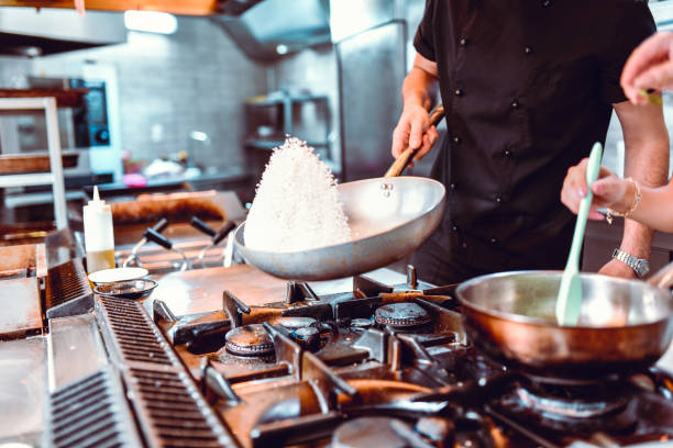 Male Cook Preparing Rice While Female Makes Sauce