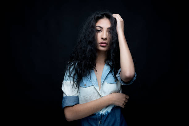 cintura para arriba / una persona / foto de la cabeza / retrato de 18-19 años de edad hermoso cabello rizado / pelo negro latino americano y etnia hispana mujer / joven mujeres adolescentes delante de fondo negro / sensualidad - one person one young woman only 18 19 years teenage girls fotografías e imágenes de stock