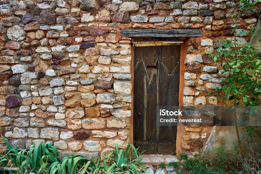Ancient wooden door in a red ochre stone wall Ancient wooden side entrance door in a red ochre garden stone wall Ancient Stock Photo