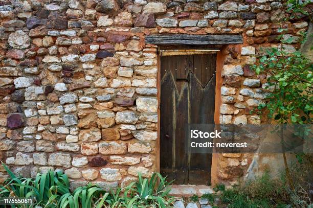 Ancient Wooden Door In A Red Ochre Stone Wall Stock Photo - Download Image Now - Ancient, Antique, Architecture