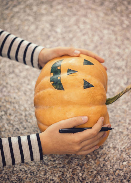 istock Young girl making Jack-o-Lantern from pumpkins, she preparing for Halloween celebration 1175551264