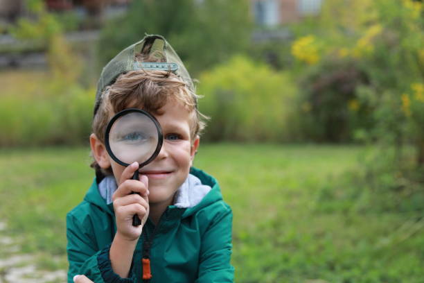 istock Little boy with magnifying glass outdoors 1175552354