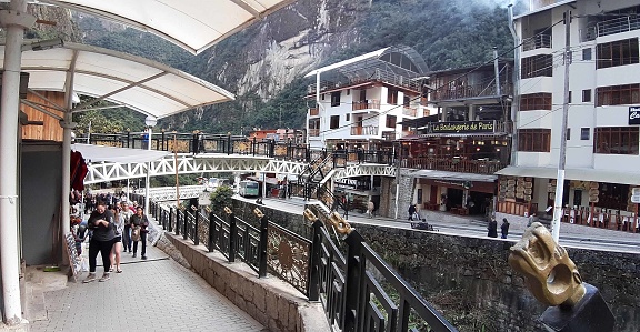 Scene Of Bus, Andes Mountain, Building Exterior, Retail Store, People Sitting Down, Standing, Walking Around And More At Aguas Calientes City Center In Cusco Peru South America