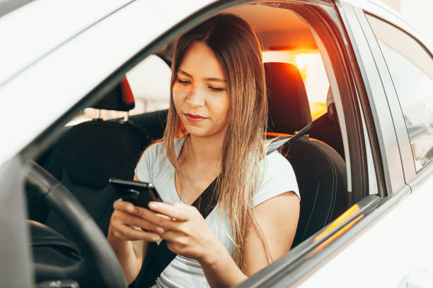 istock Woman driver sitting behind the steering wheel reading a text message on a mobile 1175554047