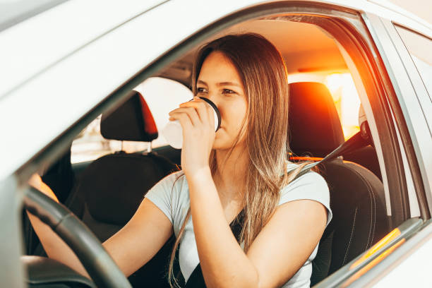 istock Woman driving and holding a coffee cup 1175554092