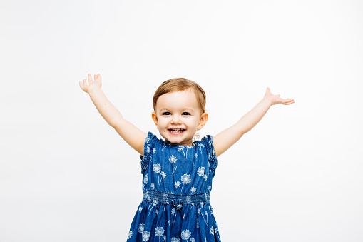 very happy toddler girl with arms outstretched up and a victorious smile, isolate din a studio
