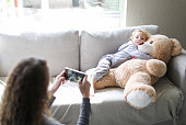 a Toddler poses for a picture with a big teddy bear.