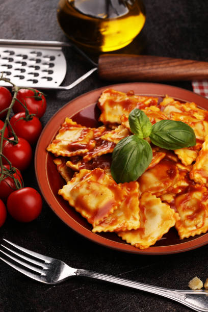 istock Ravioli with tomato sauce garnished with parmesan cheese and basil on rustic table 1175558325